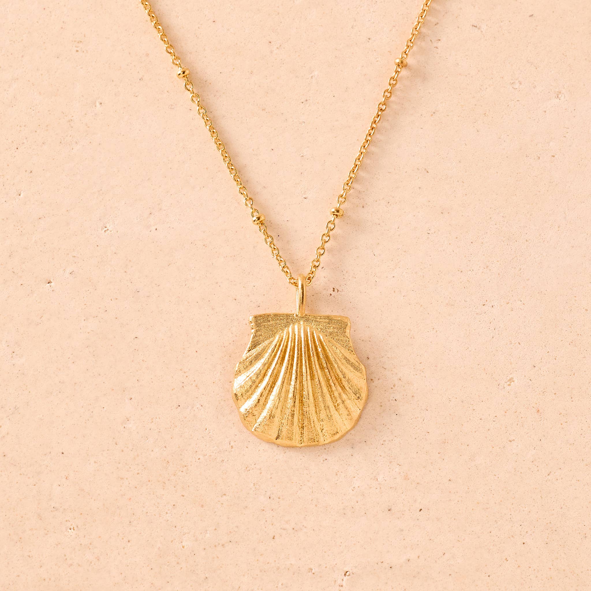 Agapée Milos gold necklace with a detailed shell pendant and satin finish