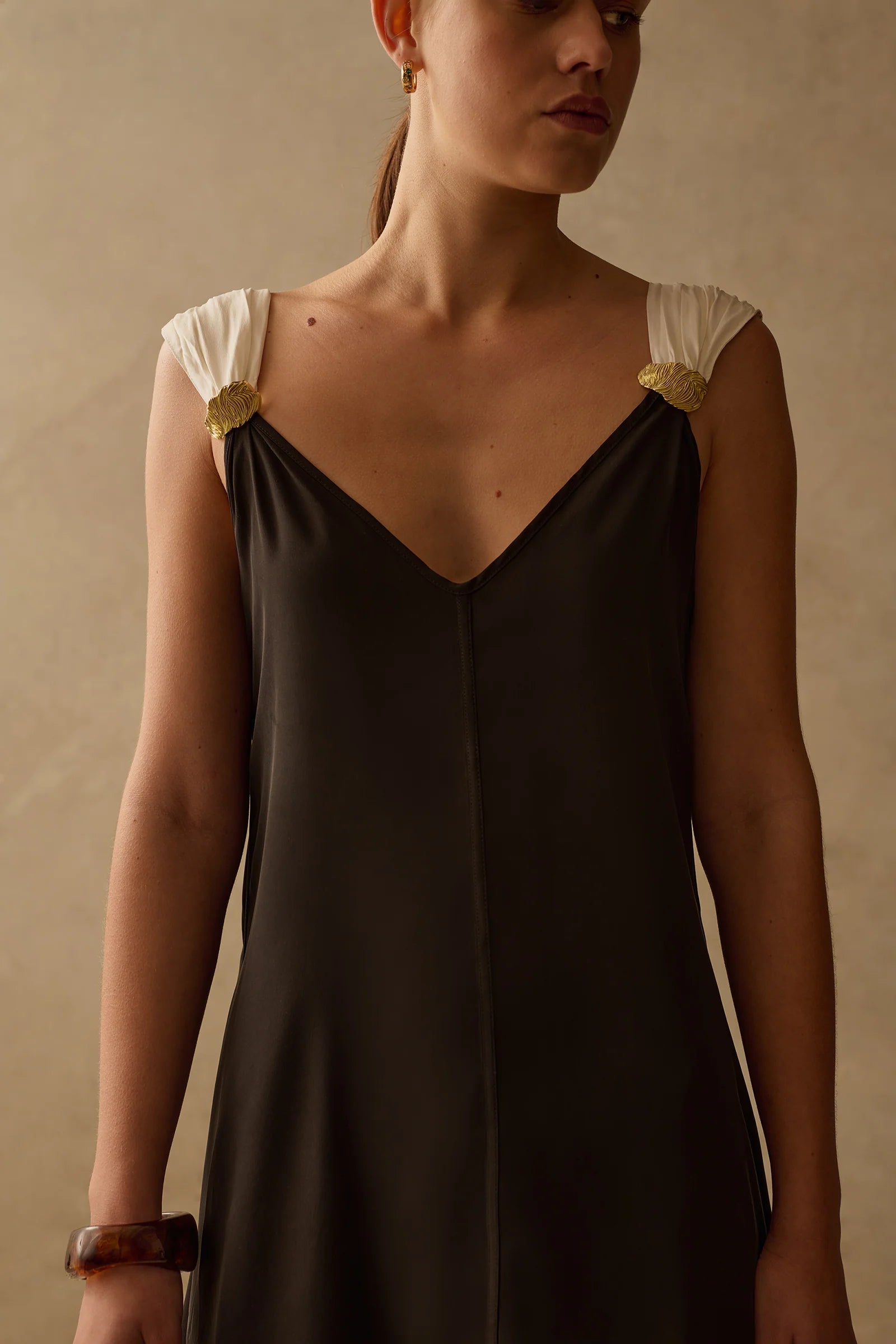 The Fia mini dress in Onyx black with ruched straps and gold brooch details