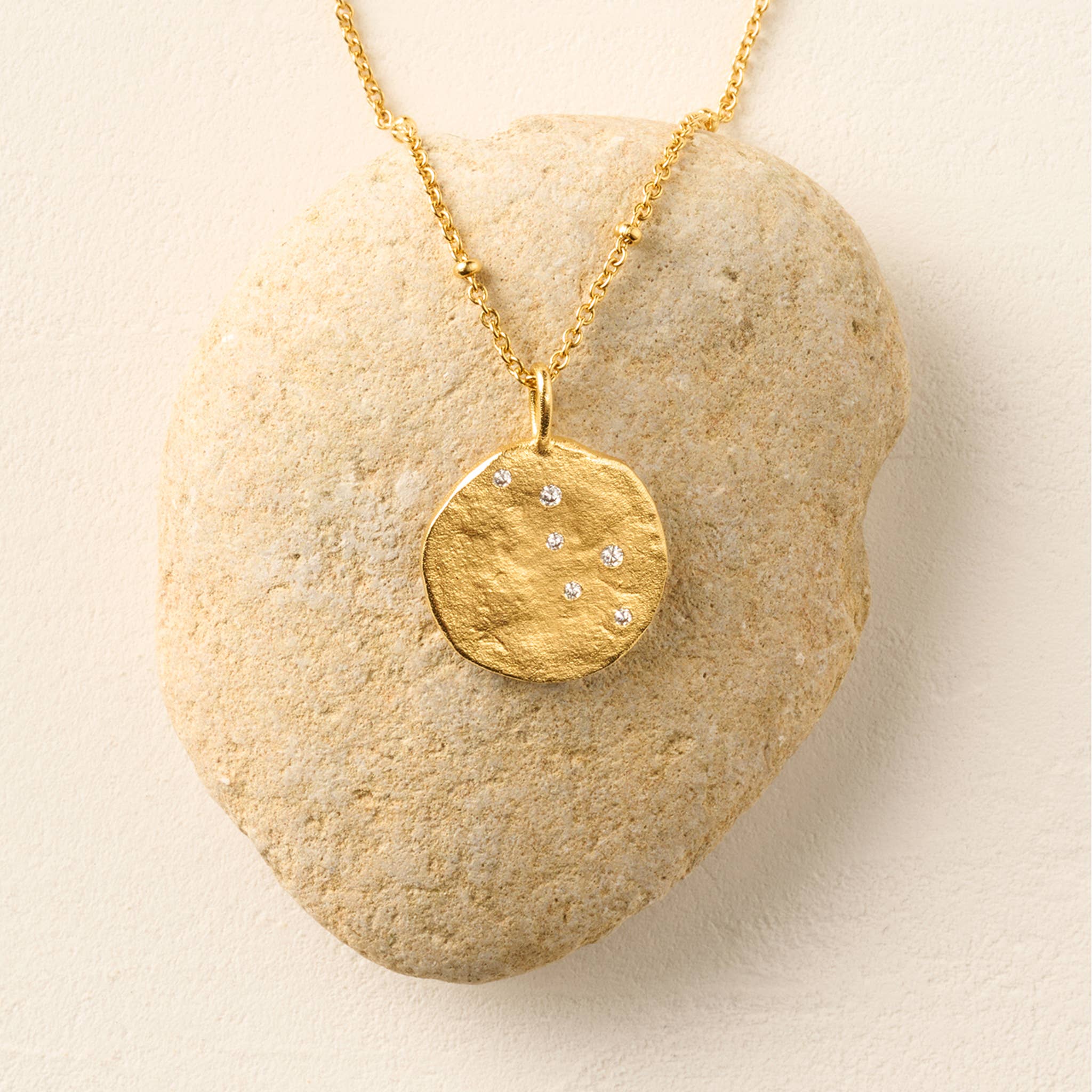 Agapée Lumoria textured satin gold-plated disc pendant necklace inlaid with star-like white cubic zirconia stones.
