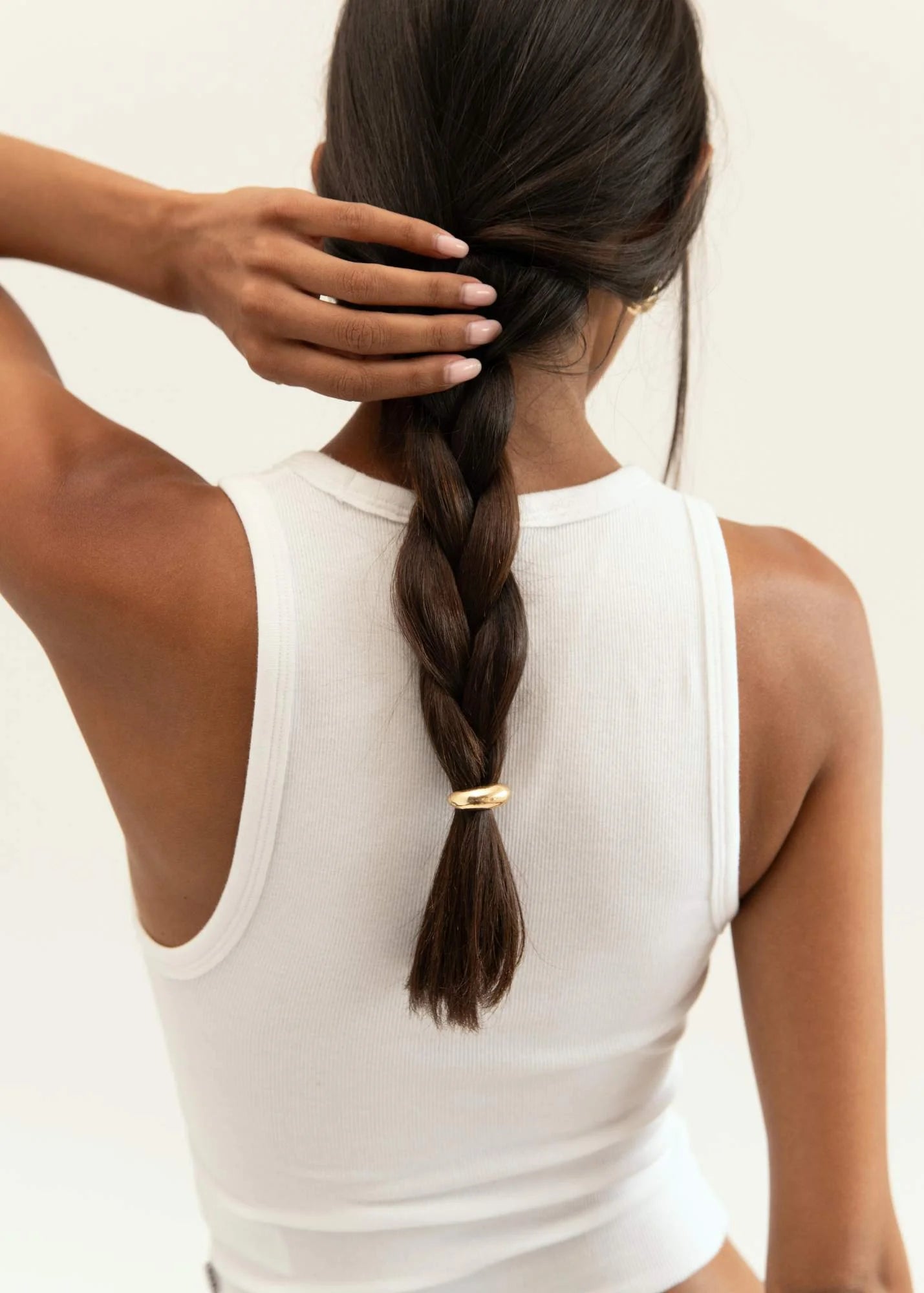 Model wearing three stacked gold hair cuffs in a long braid