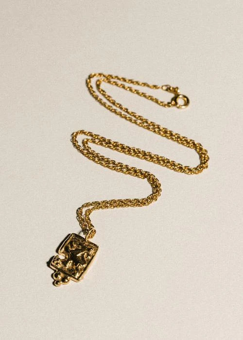 Pamela Card fractured gold amulet necklace featuring a hand-carved lioness and beaded pyramid detail.