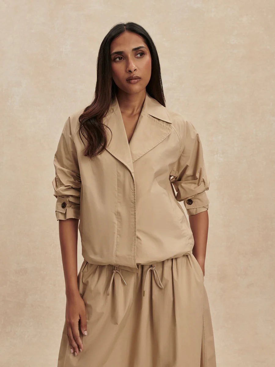 Varley Petra lightweight cotton blouson jacket in sand-toned Nomad beige featuring a point collar, raglan sleeves, and adjustable toggle hem.