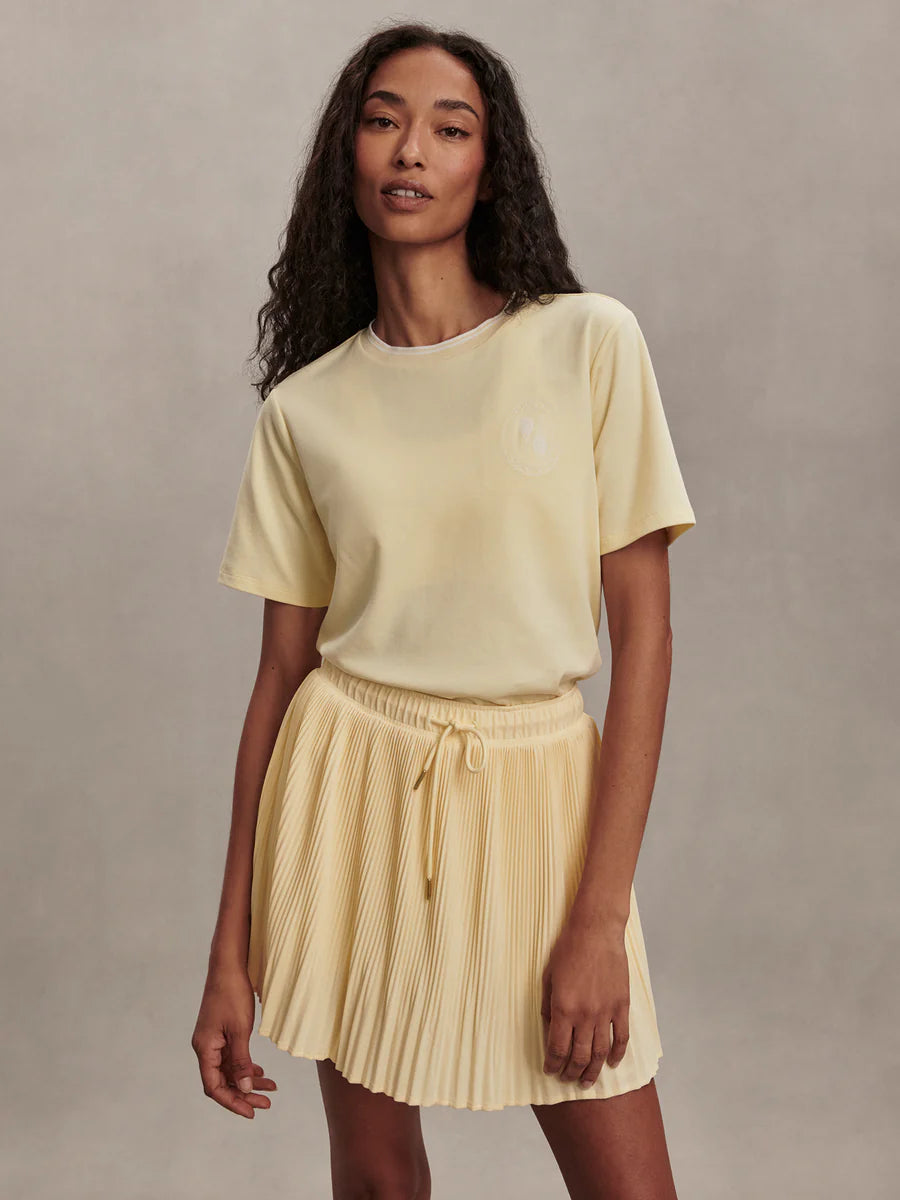 Varley Davina 15-inch high-rise pleated active skort in Anise Flower yellow featuring a gathered waistband and integrated shorts.