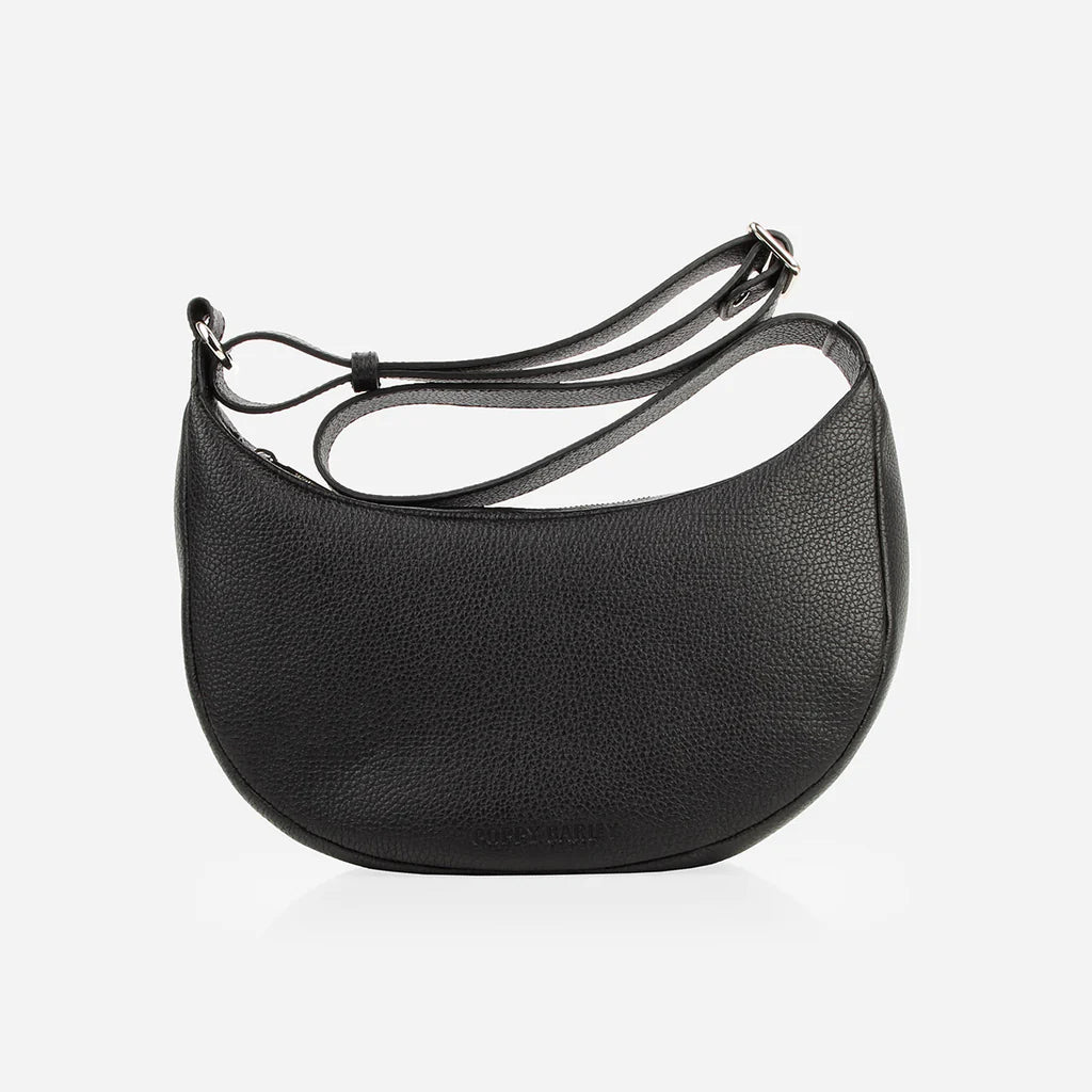 Poppy Barley The Arc structured black pebbled leather crossbody bag with adjustable strap.