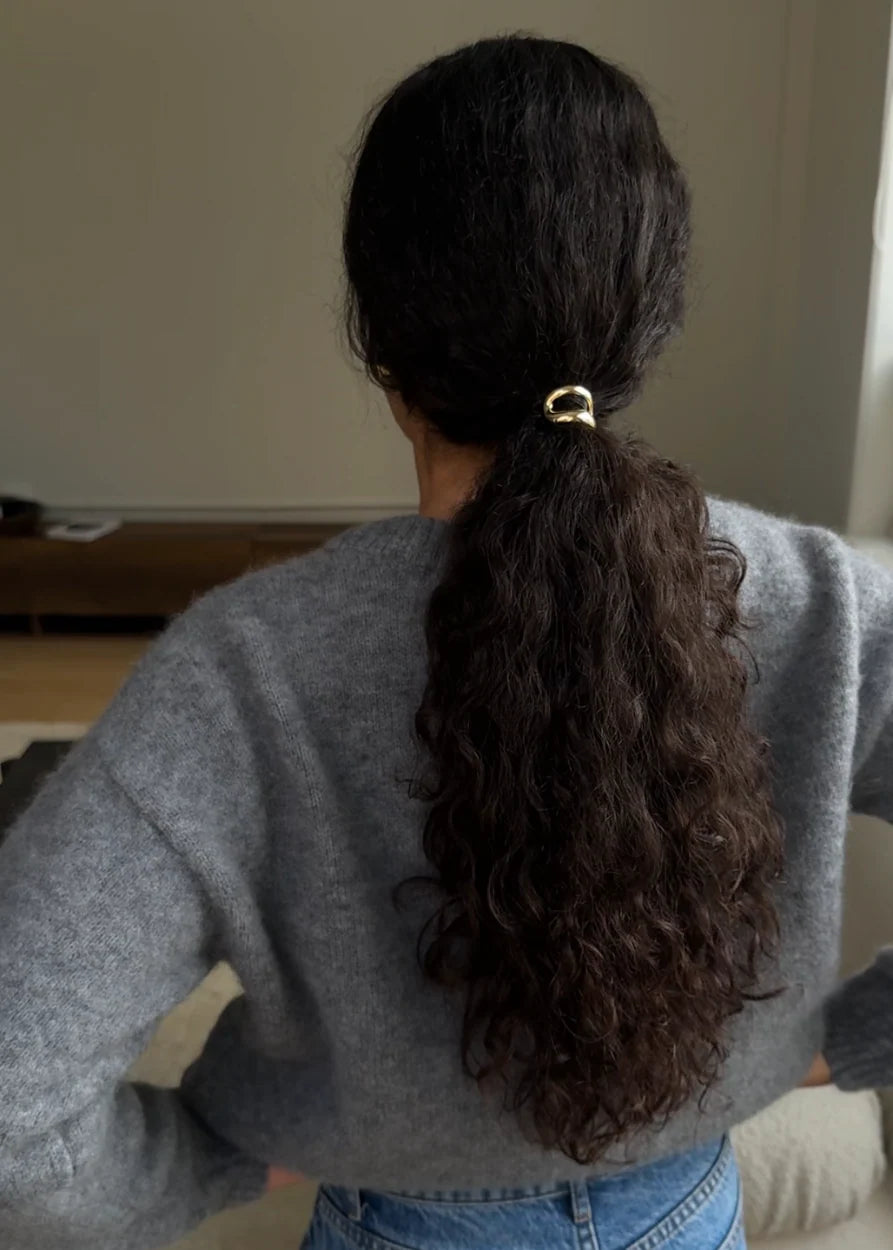 Close up of gold alloy hair cuff covering a black hair elastic