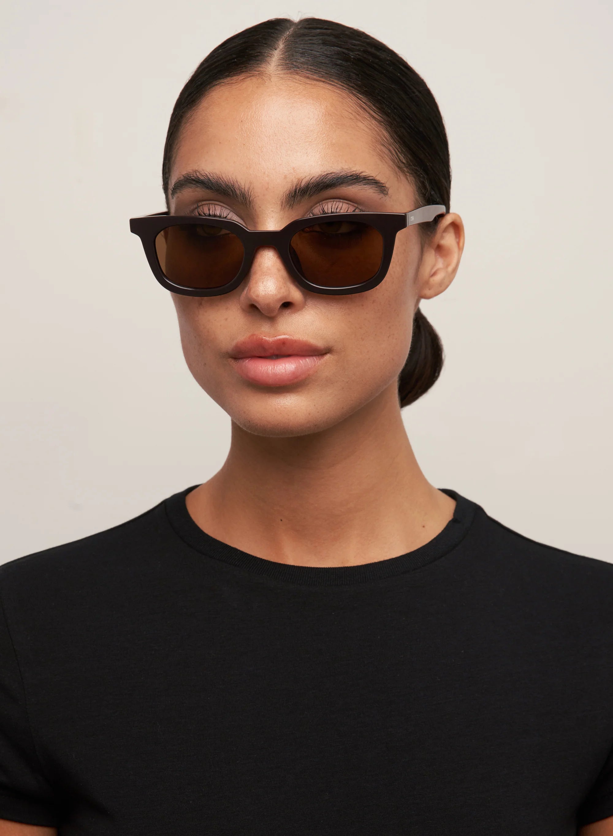 OTRA Eyewear Nia wayfarer-style square sunglasses in a rich dark chocolate frame with warm brown lenses.