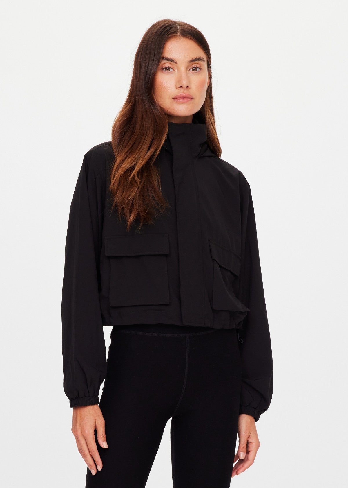 The Upside Ace cropped shell zip-through jacket in black featuring a high neck, front snap-button details, and an adjustable drawcord waist.