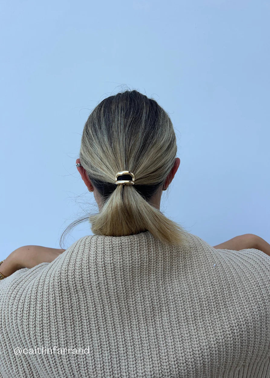 Close up of gold alloy hair cuff covering a black hair elastic